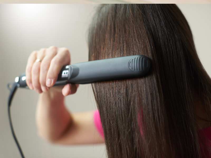 woman-styling-hair-with-a-heat-styling-tool