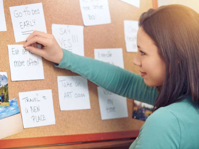 woman-pinning-notes-on-the-corkboard-at-home-to-set-plans-for-special-child