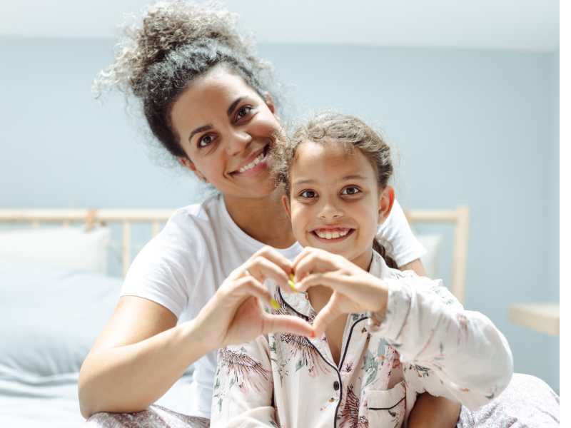 mother-and-daughter-in-bed-showing-love-symbol