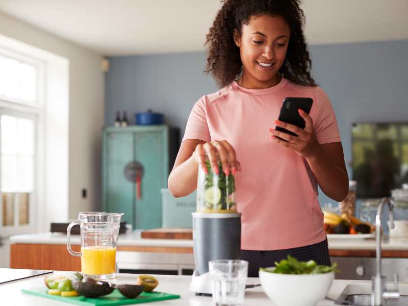 woman-in-the-kitchen-with-phone-in-hand-using-technology-to-manage-daily-tasks-as-a-new-mom