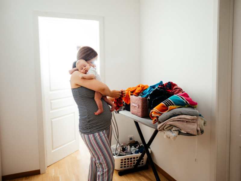 mom-carrying-baby-fixing-laundry