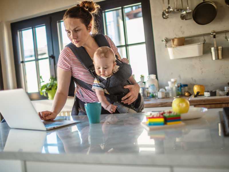 woman-with-baby-in-the-kitchen-using-laptop