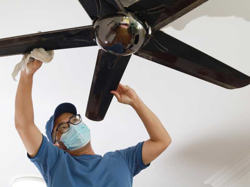 a-young-man-on-bleu-clothing-cleaning-ceiling-fan