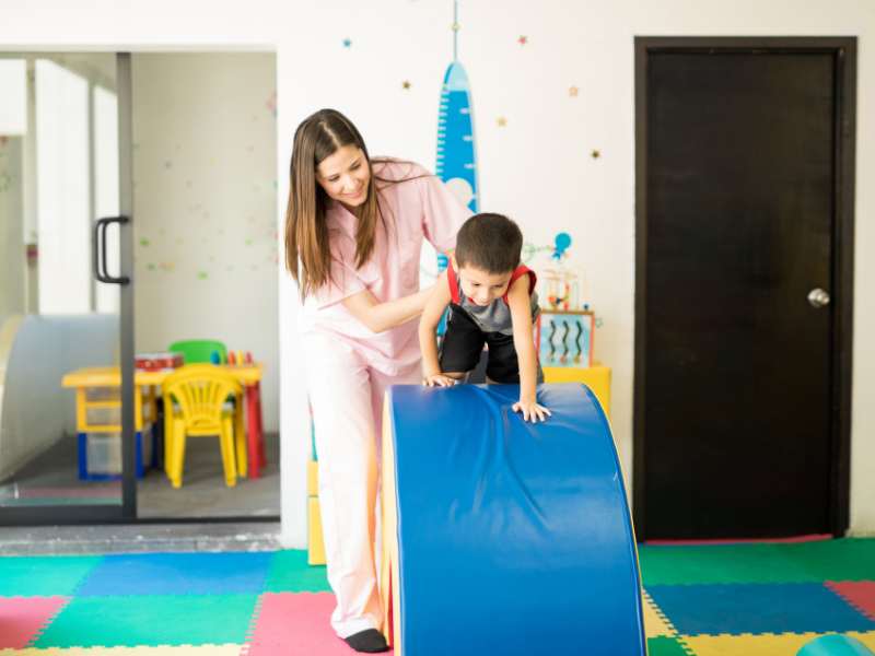 little-boy-crawling-through-the-obstacle-course-with-the-help-of-a-woman