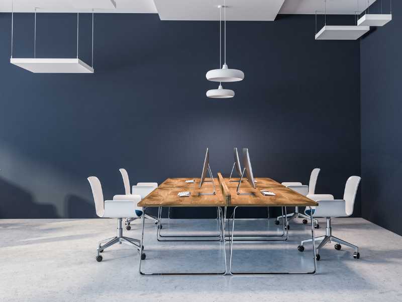 a-brown-fold-down-desk-with-white-chairs-in-a-big-open-space