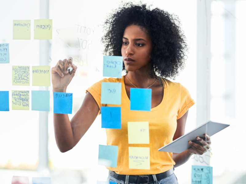 woman-on-yellow-top-pinning-her-plan-on-the-board