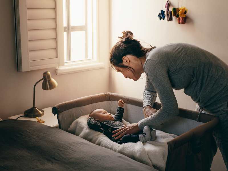 woman-bending-to-check-baby-on-crib-a-healthy-development-in-babies