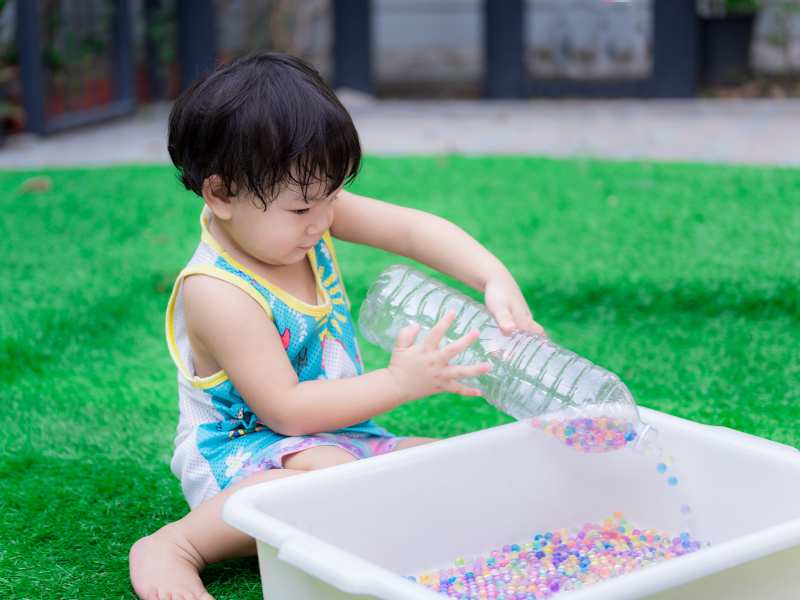 little-boy-playing-with-sensory-bottles-outside