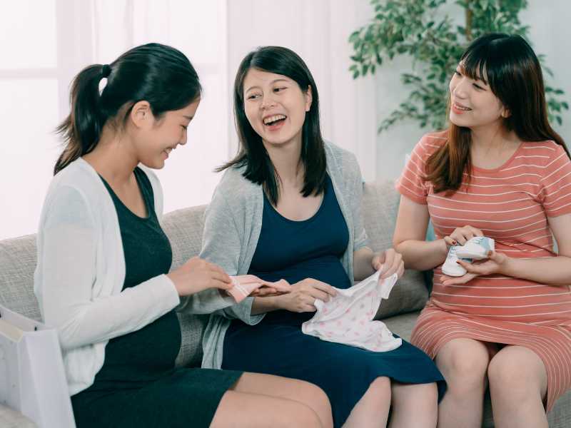 woman-with-friends-holding-baby-clothes-a-challenge-faced-by-new-moms