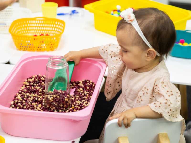 toddler-playing-sensory-game-with-bowl-of-red-beans