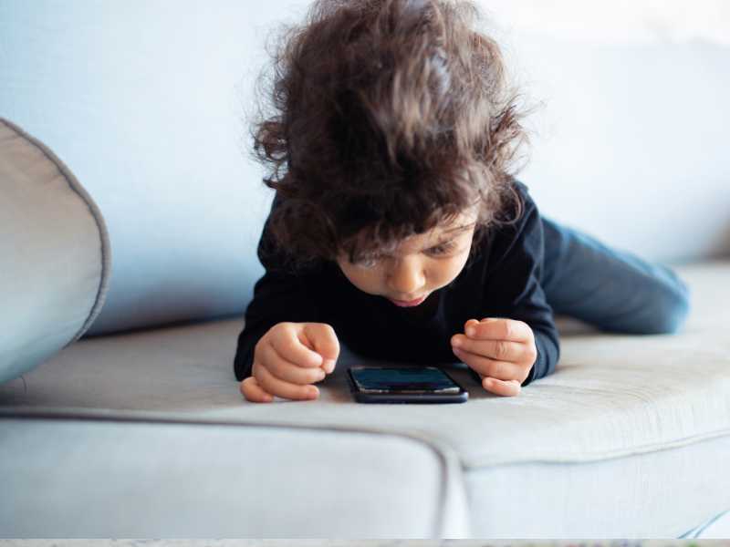 little-girl-lying-on-sofa-with-phone