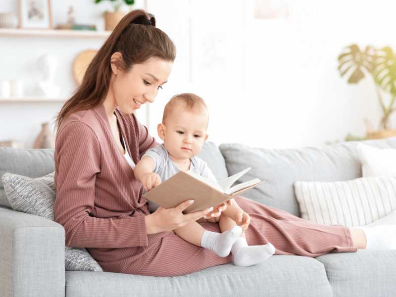 mom-reading-aloud-for-baby-at-home-relaxing-on-couch-in-living-room