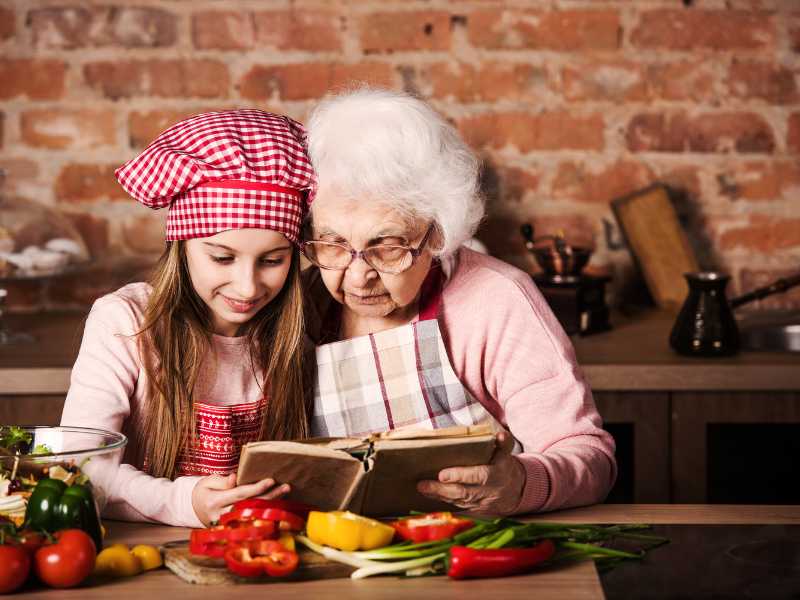 an-old-woman-with-a-young-woman-looking-into-a-book-with-apron