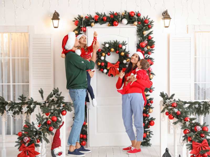 a-family-of-four-standing-in-front-of-a-white-door-with-Christmas-decorations