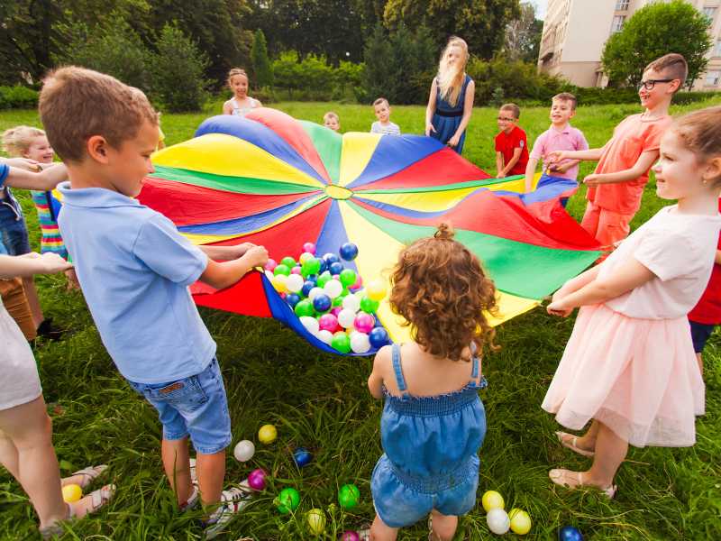 children-playing-ball-rainbow-parachute