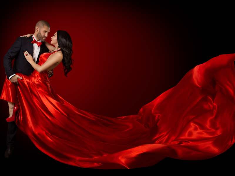 man-on-suit-with-lady-on-red-gown-in-dark-background