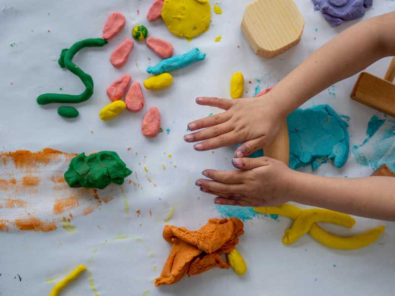 hard-rolling-a-play-dough-of-blue-colour-on-a-blue-board-surface 