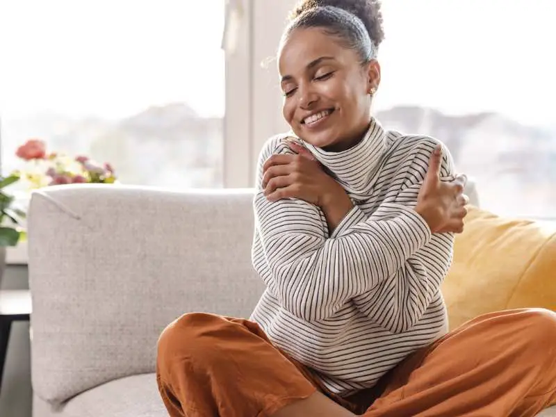 a-beautiful-woman-sitting-on-sofa-hugging-herself