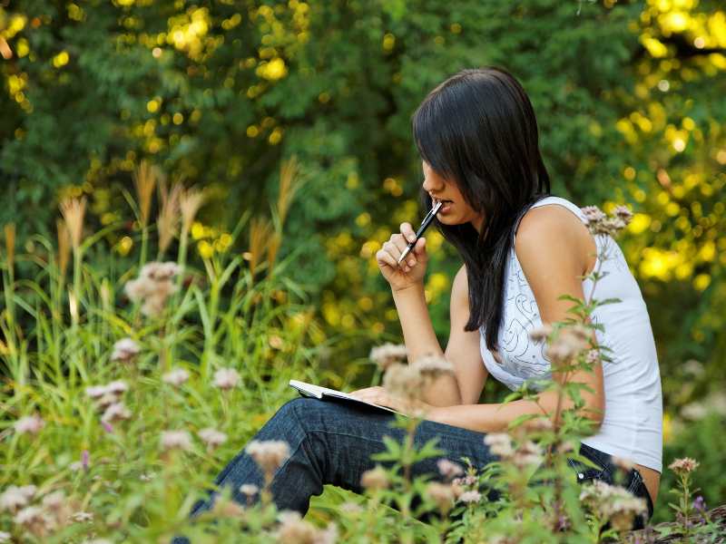 WOMAN-SITTING-OUTSIDE-WWITH-A-JOURNAL-REFLECTING