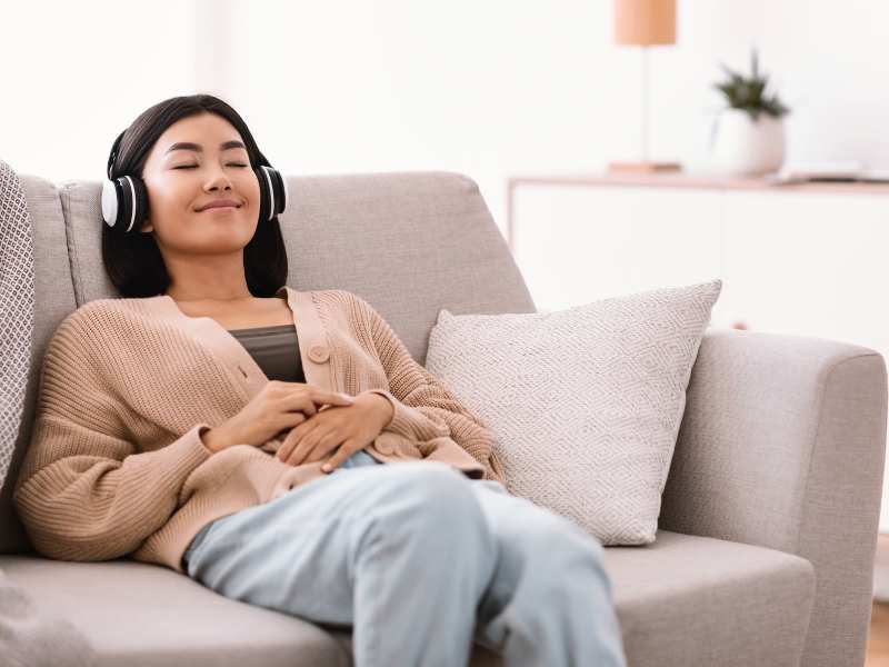 asian-woman-lying-on-the-couch-listening-to-music-an-ideal-self-care-tips-for-moms-on-mother's-day