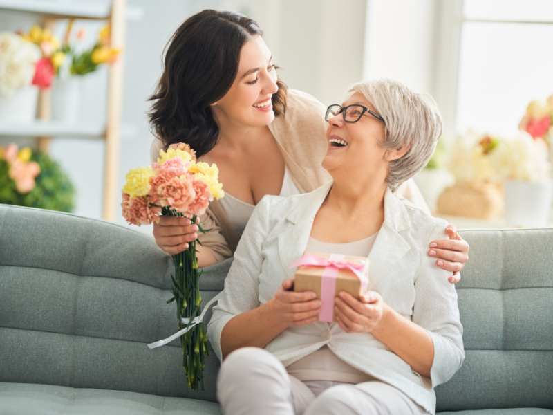 YOUNG-WOMAN-PRESENITNG-TO-AN-OLDER-WOMAN-WITH-MOTHER'S-DAY-GIFT