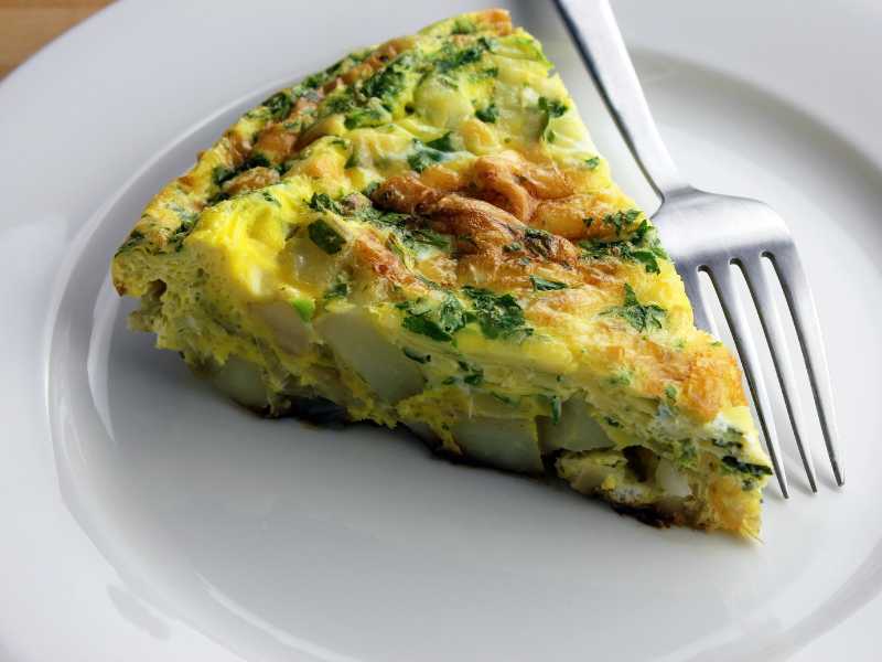 a-slice-of-vegetable-frittata-in-a-white-flat-plate