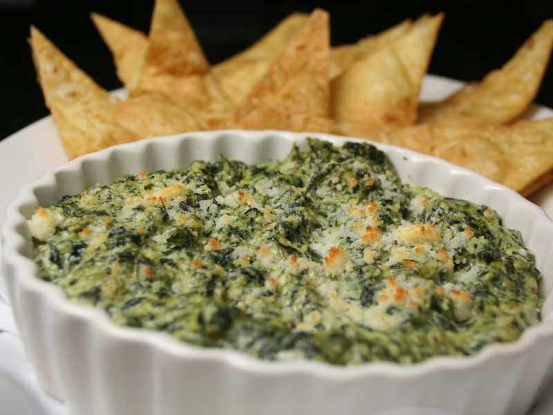 vegan-spinach-in-a-white-bowl-and-artichoke-in-a-white-flate-plate