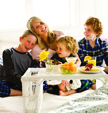 mom-with-kids-on-bed-taking breakfast