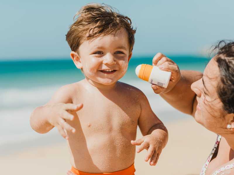 mom-with-sunscreen-for-baby-to-survive-summer-vacation-with-a-new-born
