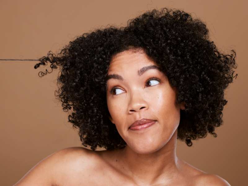 lady-detangling-4C-hair-on-a-brown-background